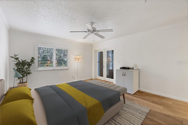 bedroom featuring ceiling fan, a textured ceiling, light wood-type flooring, and crown molding