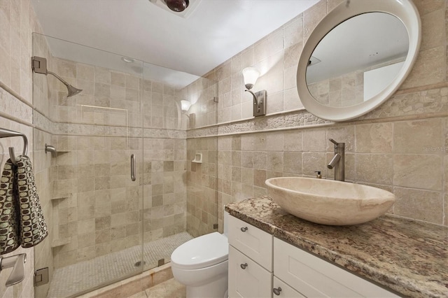 bathroom with toilet, vanity, an enclosed shower, and tile walls