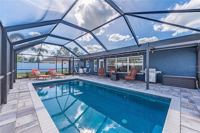 view of pool featuring glass enclosure, a patio area, and a grill