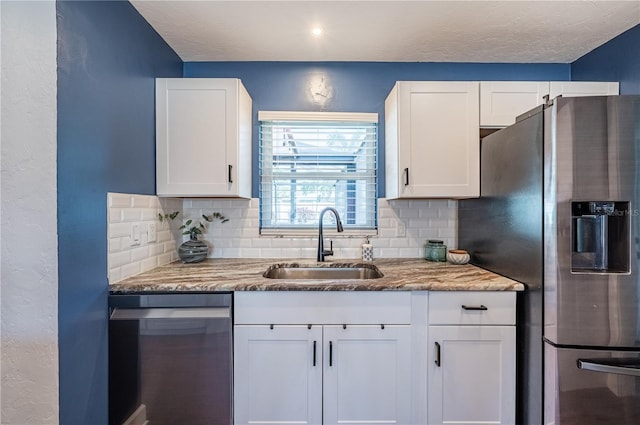 kitchen with backsplash, white cabinets, sink, and stainless steel appliances