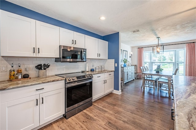 kitchen featuring white cabinets, hardwood / wood-style floors, appliances with stainless steel finishes, and hanging light fixtures