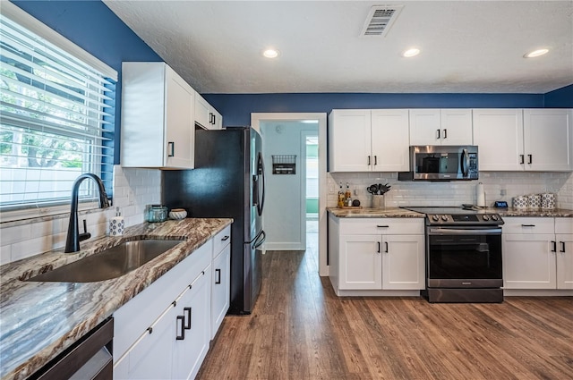 kitchen with white cabinetry, hardwood / wood-style floors, stainless steel appliances, and sink