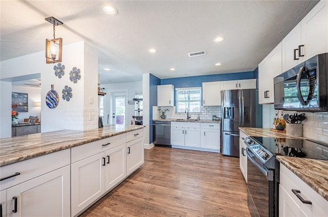 kitchen featuring stainless steel appliances, white cabinets, light stone counters, and hardwood / wood-style floors