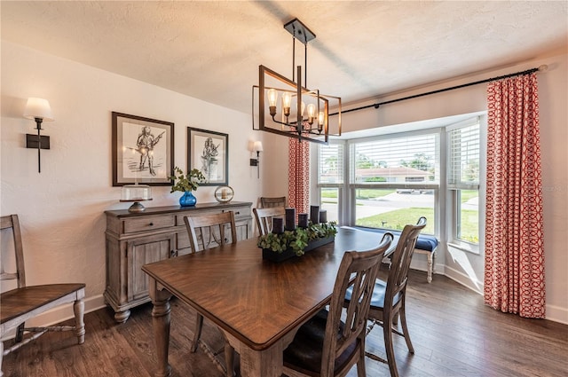 dining area featuring dark wood-type flooring, an inviting chandelier, and a textured ceiling