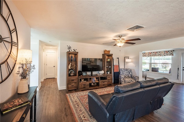 living room featuring a textured ceiling, dark wood-type flooring, and ceiling fan