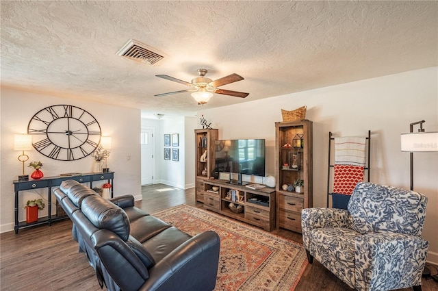 living room featuring dark hardwood / wood-style flooring, a textured ceiling, and ceiling fan