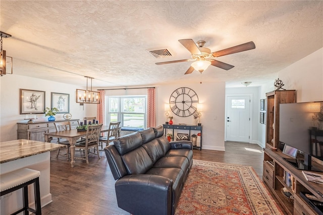 living room featuring a textured ceiling, dark hardwood / wood-style floors, and ceiling fan with notable chandelier