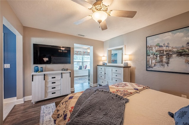 bedroom featuring dark wood-type flooring, ceiling fan, and a textured ceiling