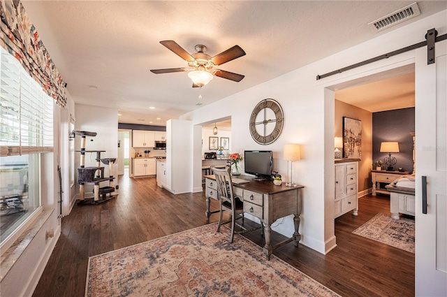 office with ceiling fan, dark hardwood / wood-style floors, and a barn door