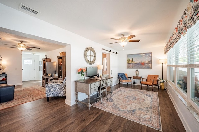 office space featuring a barn door, dark hardwood / wood-style floors, and ceiling fan