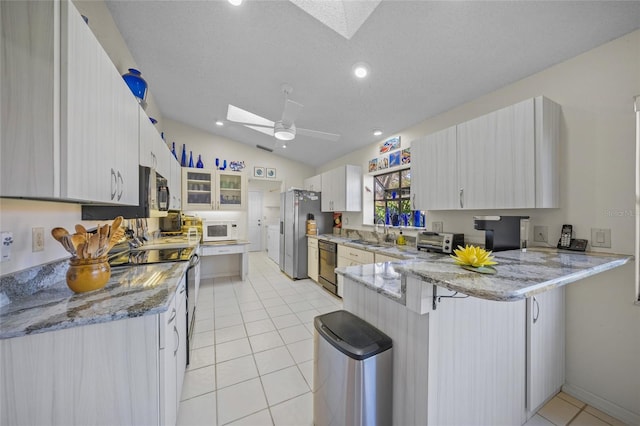 kitchen with lofted ceiling with skylight, kitchen peninsula, appliances with stainless steel finishes, and a kitchen bar