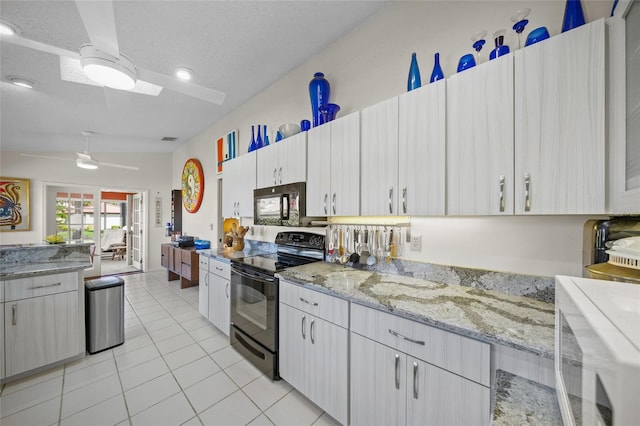 kitchen with black appliances, a textured ceiling, lofted ceiling, and light tile patterned floors