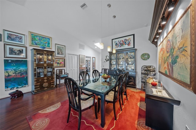 dining room with dark wood-type flooring and vaulted ceiling