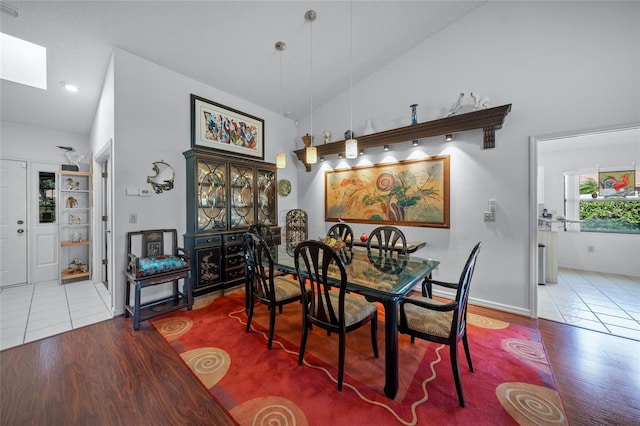 dining area with high vaulted ceiling and tile patterned floors