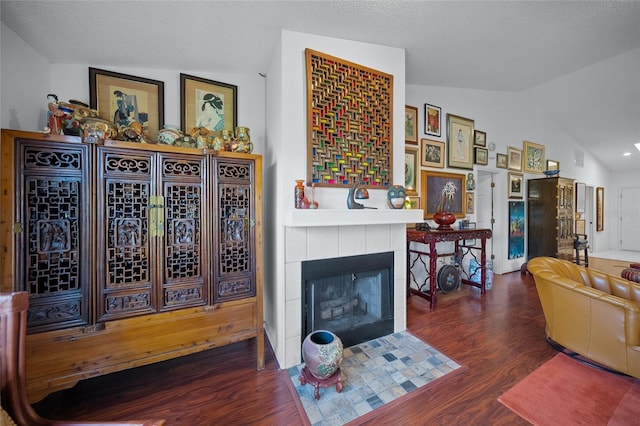 living room featuring dark hardwood / wood-style flooring, a tiled fireplace, and lofted ceiling