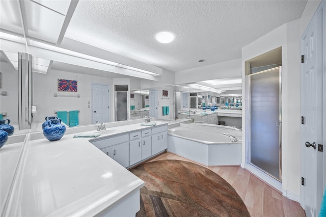 bathroom with vanity, shower with separate bathtub, hardwood / wood-style floors, and a textured ceiling