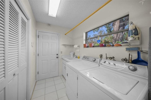 laundry room featuring cabinets, a textured ceiling, sink, light tile patterned floors, and washer and clothes dryer