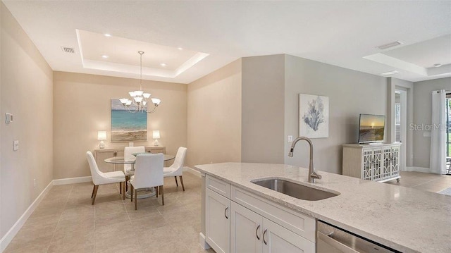 kitchen featuring light stone counters, hanging light fixtures, a chandelier, sink, and white cabinetry