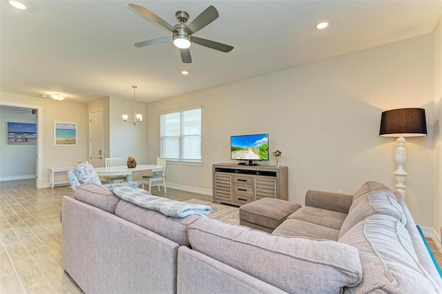 living room with ceiling fan with notable chandelier and light hardwood / wood-style flooring