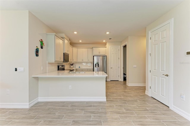 kitchen featuring kitchen peninsula, stainless steel appliances, decorative backsplash, and sink