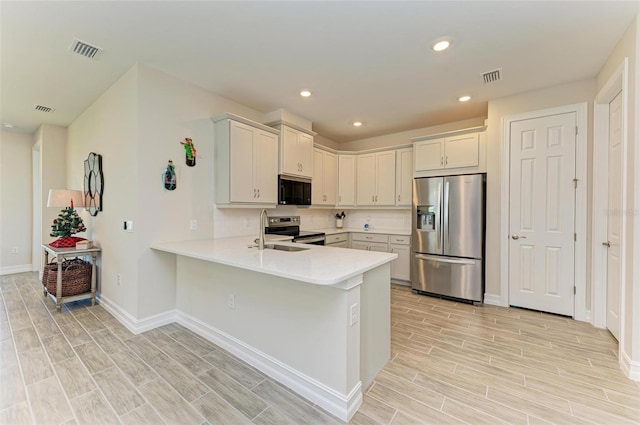 kitchen featuring kitchen peninsula, appliances with stainless steel finishes, sink, and light hardwood / wood-style flooring