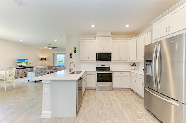 kitchen with white cabinets, kitchen peninsula, sink, light wood-type flooring, and appliances with stainless steel finishes