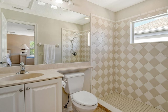 bathroom with vanity, toilet, and a tile shower