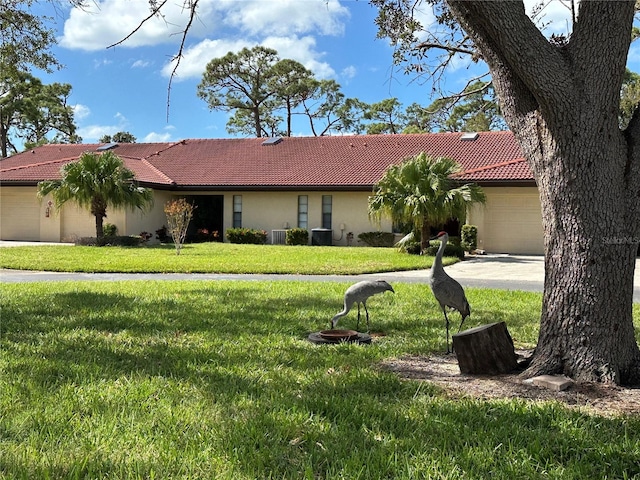 ranch-style house featuring central AC unit, a garage, and a front lawn