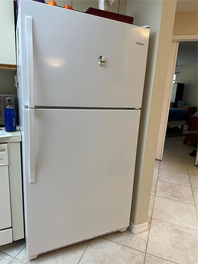 kitchen featuring white cabinets, light tile patterned floors, and white refrigerator