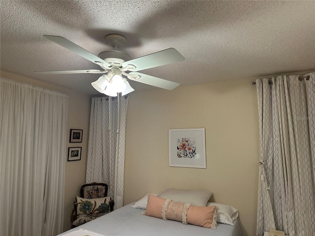 bedroom with ceiling fan and a textured ceiling