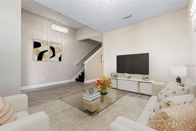 living room with an inviting chandelier, wood-type flooring, and a textured ceiling