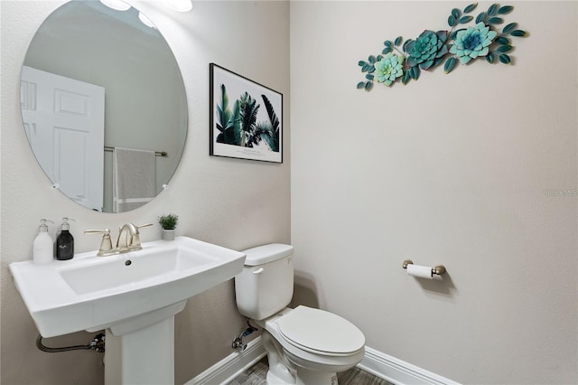 bathroom featuring wood-type flooring, toilet, and sink