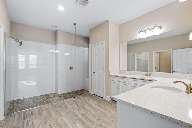 bathroom featuring tiled shower, hardwood / wood-style floors, and vanity