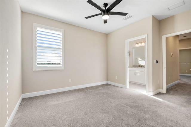 unfurnished bedroom featuring light carpet, ceiling fan, and ensuite bath