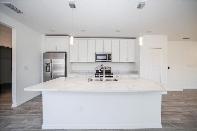 kitchen with white cabinetry, appliances with stainless steel finishes, decorative light fixtures, and an island with sink