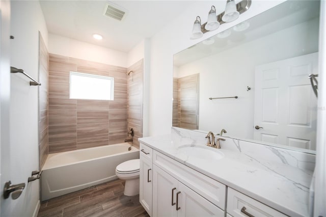 full bathroom with hardwood / wood-style floors, tiled shower / bath, toilet, and vanity