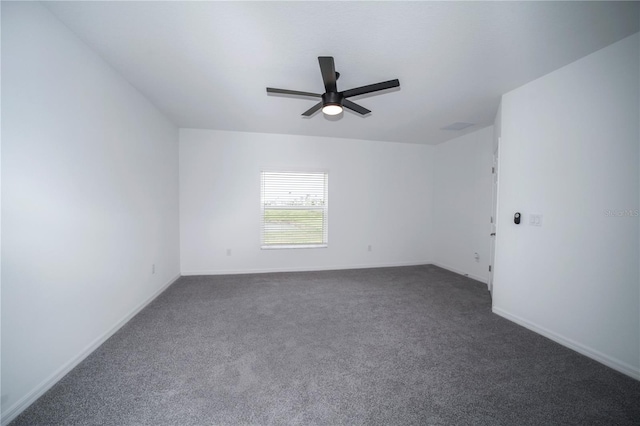 spare room featuring dark colored carpet and ceiling fan