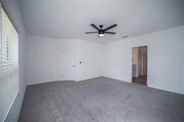 empty room featuring ceiling fan and dark colored carpet