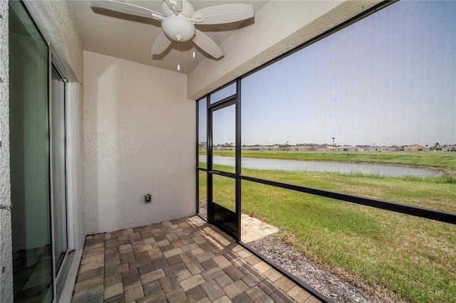 unfurnished sunroom with ceiling fan and a water view