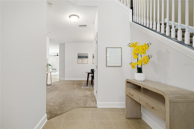 corridor featuring a textured ceiling and light carpet