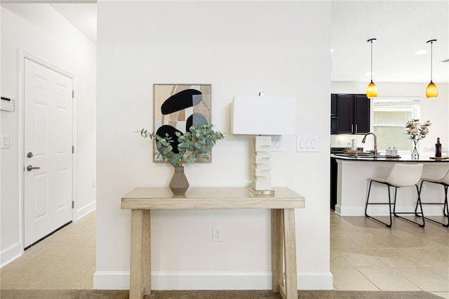 interior space with kitchen peninsula, light tile patterned floors, sink, a breakfast bar, and pendant lighting