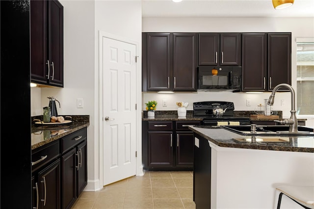 kitchen featuring dark brown cabinets, dark stone countertops, light tile patterned floors, and black appliances