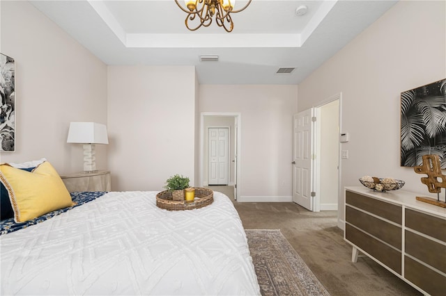 bedroom featuring a tray ceiling, an inviting chandelier, and light colored carpet