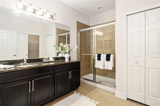 bathroom featuring vanity, tile patterned floors, and a shower with door