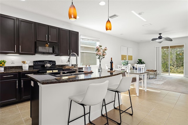 kitchen featuring black appliances, light carpet, an island with sink, ceiling fan, and pendant lighting