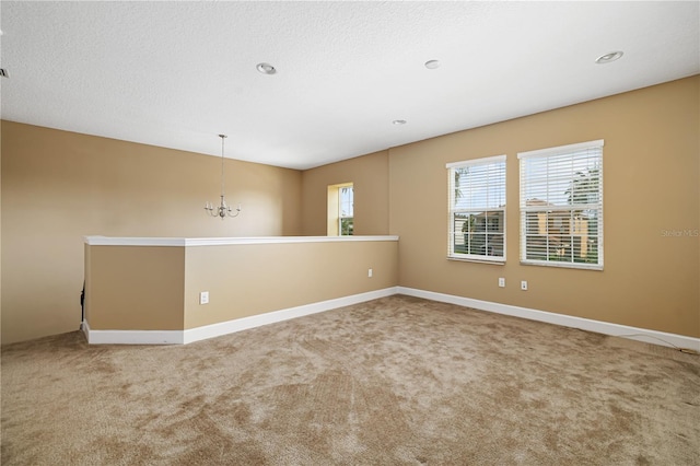 carpeted spare room with an inviting chandelier