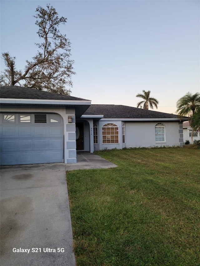 single story home featuring a garage and a yard