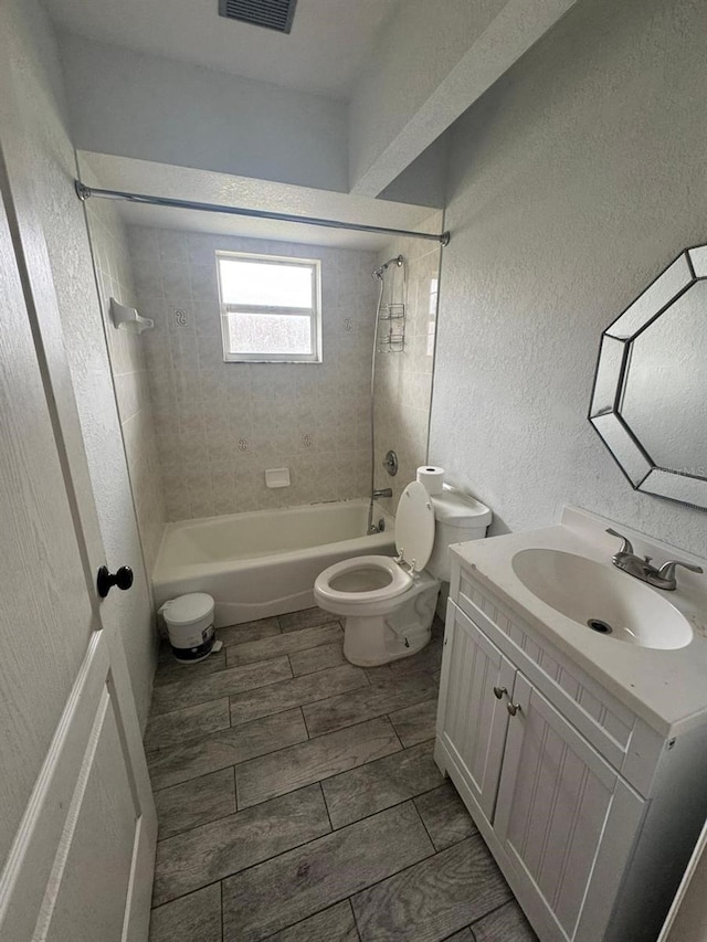 full bathroom featuring vanity, tiled shower / bath, and toilet