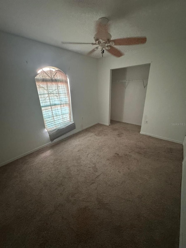 unfurnished bedroom with a closet, a textured ceiling, carpet flooring, and ceiling fan