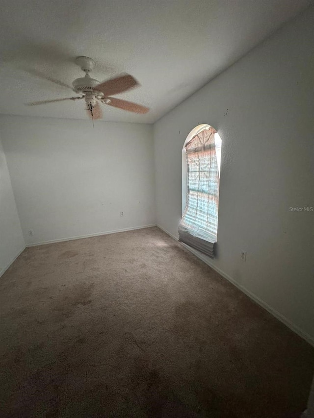 carpeted spare room featuring a textured ceiling and ceiling fan